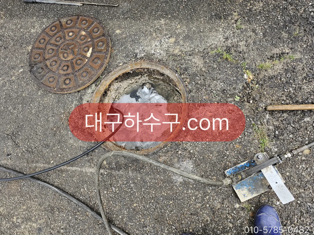 맨홀을 열고 고압세척 호스를 넣은 작업 현장
