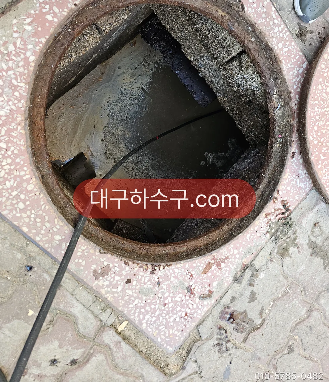 옥외 맨홀을 열고 고압 호스를 넣는 작업