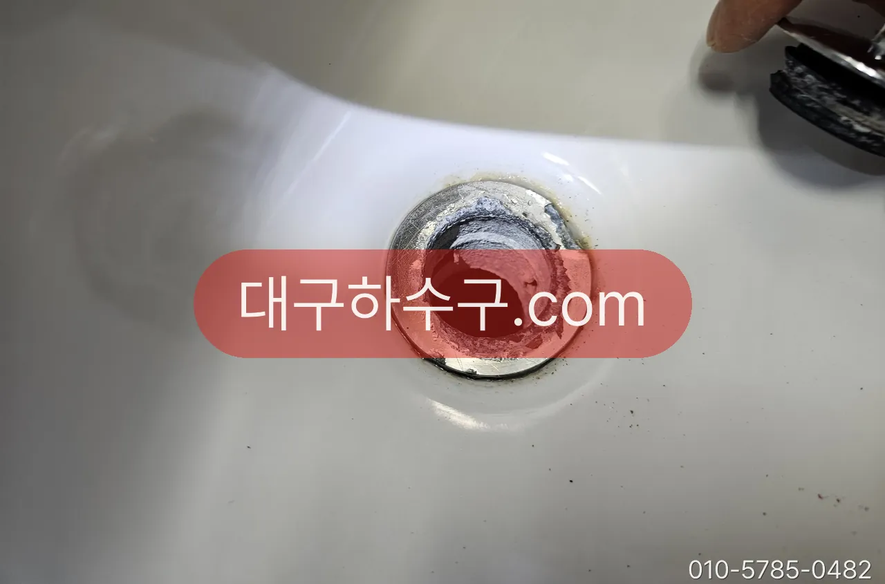 팝업 마개를 뺀 세면대 배수구 — 십자 살에 머리카락이 감기는 자리